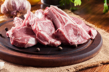 Raw fresh lamb chops on wooden cutting board