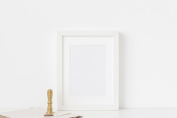 Stylish white a5 portrait frame mockup with gold stamp and printing on white wall background. Empty frame, poster mock up for presentation design. Template frame for text, lettering, modern art.