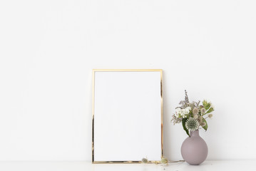 Minimal gold 5 aportrait frame mockup with dried field wild flowers in pot on white wall background. Empty frame, poster mock up for presentation design.