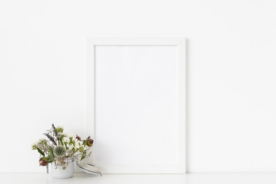 White a4 portrait frame mockup with dried field wild flowers in pot on white wall background. Empty frame, poster mock up for presentation design. Template frame for text, lettering, modern art.