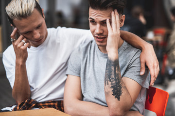 Disappointed men holding temple with hand while thinking and speaking together. The guy having...