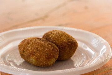 Two tasty croquettes on plastic plate. Delicious snack, homemade Spanish traditional food concepts