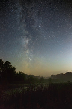 Starry night sky in the northern hemisphere. View of the Milky Way over a lake with a mist. Long exposure.