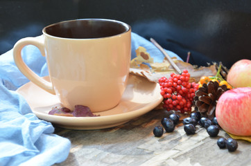 Flat lay of composed cup with black coffee on wood table with ripe berries of rowan and dark foliage. Cappuccino or latte or tea on a vintage table. fallen leaves, ripe apples, berries. Copy space