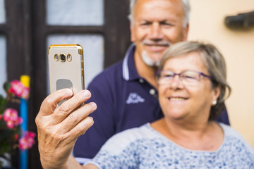 cheerful happy old mature adult man and woman taking selfie with the phone at home. smiles and happiness using phone to communicate with parents and son or daughters. video conference and live call.