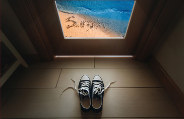 Keds stand near the door on the background of the summer beach. The inscription on the sand is summer.Tour, freedom, vacation concept.