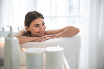 Portrait of beaming lady with attractive smile resting in bathroom in apartment