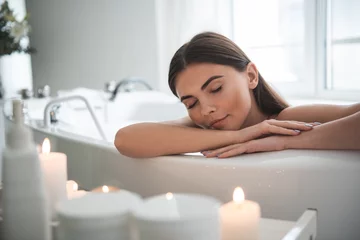 Washable wall murals Spa Portrait of serene female leaning on side of bath while resting there. Calm lady having leisure during spa procedure concept