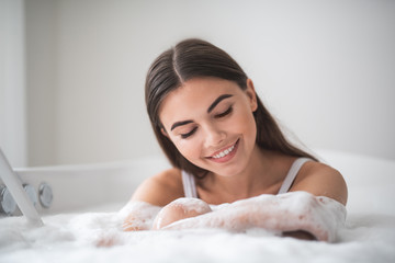 Naklejka premium Portrait of beaming girl having leisure in cozy bath. She gesticulating hands. Optimistic female during spa procedure concept