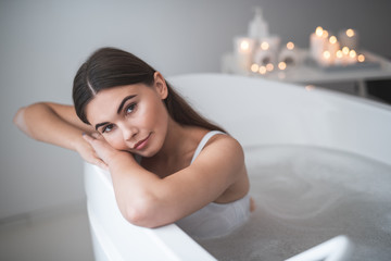 Portrait of pensive girl lying in warm water during treatment. She looking at camera. Healthcare concept