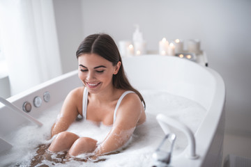 Portrait of optimistic female relaxing during treatment procedure in water. She closing eyes