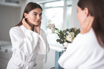 Portrait of pleased woman watching at reflection while gesticulating hands. Beautiful flowers...