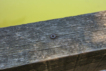 Old wooden board in bad condition with metal screw in the middle.