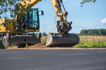 Frontal excavator pushing a gravel pile around at a quarry site, next to road construction site  
