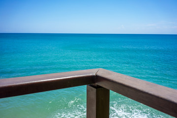 Obraz na płótnie Canvas wood hand rail and ocean horizon with turquoise water