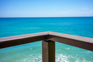 Fototapeta na wymiar wood hand rail and ocean horizon with turquoise water