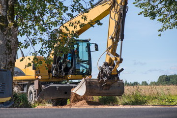 Frontal excavator pushing a gravel pile around at a quarry site, next to road construction site  
