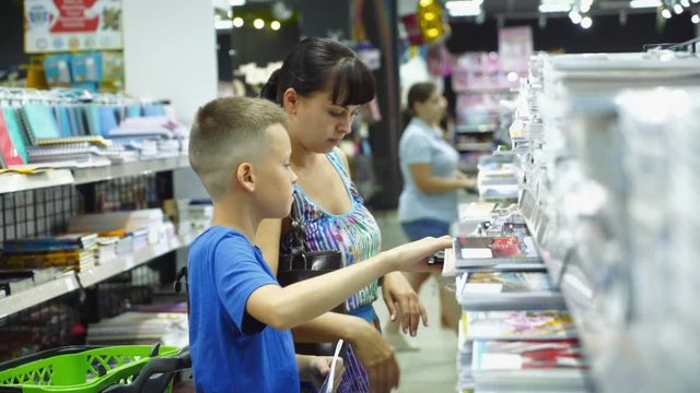 Back to school concept. Young mother and little boy buying school supplies in store.