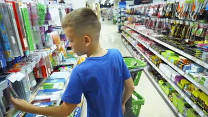 Boy choosing buying stationery in store preparing for first day in school. Back to school concept. - Powered by Adobe