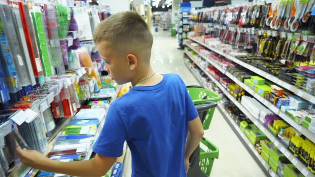 Boy choosing buying stationery in store preparing for first day in school. Back to school concept.