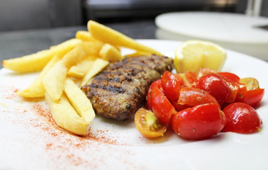 steak burger with potato fries and fresh tomatoes - greek food