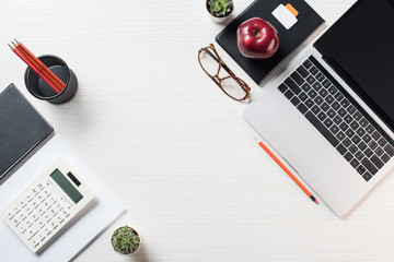 elevated view of workplace with stationery, eyeglasses, calculator and laptop on table