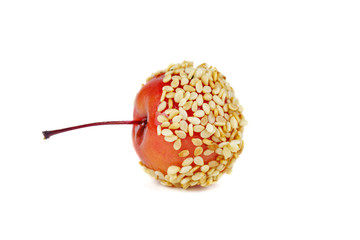 Hand dipped caramel crab apple covered with flax and sesame seeds isolated on white background