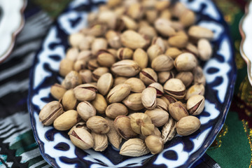 Pistachio nuts in a plate on the table. Focus with shallow depth of field, blurred background