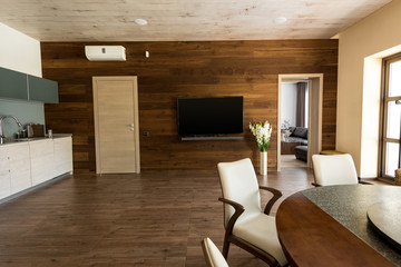 interior of modern kitchen and dining room with table, chairs and TV set