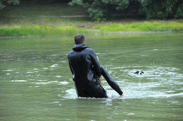 Men in a wet diver’s suits (lifeguards) showing right way of pulling a drowning out from the water