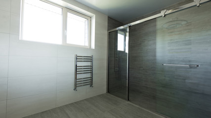 interior of empty bathroom with glass shower in grey color