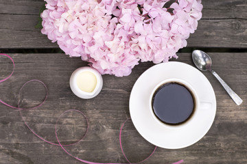 Pink hydrangea on a wooden table next to fragrant coffe