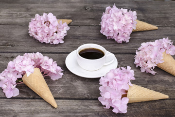 A cup of coffe on a wooden table and bouquets of hydrangea