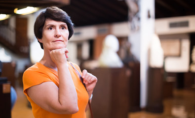 Portrait of female visitor who is looking at the exposition in historical museum.