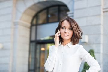 Attractive brunette businesswoman talking on mobile phone with client.