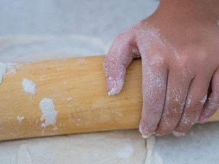 Little girl kneading dough with pin