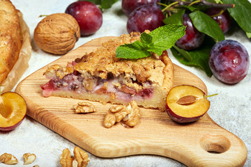 Delicious sweet pie with plums and walnuts. Closed pie. Sweet autumn dessert.
