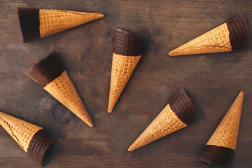 Ice cream cones pattern. Sweet Ice-cream cones with chocolate on wooden background, flat lay. Summer concept. Top view.