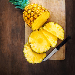 Pineapple on wood texture background. Whole and sliced tropical pineapple on wooden cutting board  with copy space. Flat lay