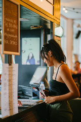 A young Asian millenial takes her time as she chooses from the menu what to order for a...