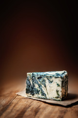 Blue cheese Gorgonzola on a rustic wooden background. Mold cheese with copyspace.