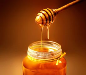 Honey in jar with honey dipper on rustic wooden table background. Copy space.