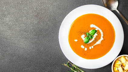 Bowl of squash soup. Copy space.  Fresh homemade pumpkin  soup with a swirl of cream. Top view.