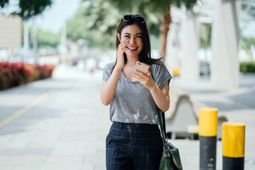 Portrait of a Japanese Asian woman tourist in the streets in Singapore. She is young, attractive and is wearing comfortable and casual clothes as she wanders the sunny streets.