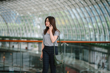 A portrait of a Japanese tourist woman talking on her smartphone. She looks very happy to be out in a new city.