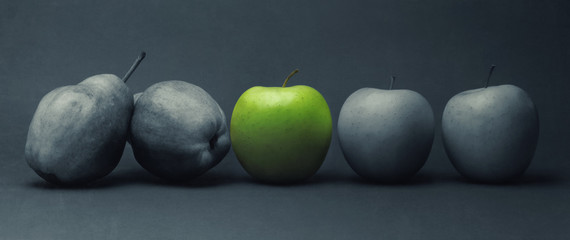 Close-up of green apple between gray fruit, still life