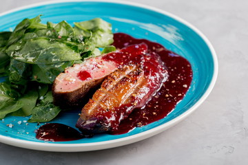 Duck breast with spinach leaves and berry sauce.