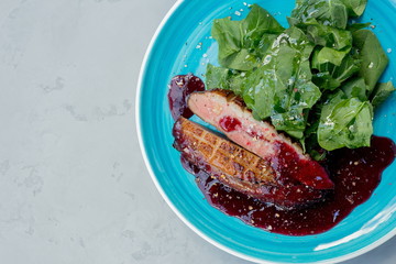 Duck breast with spinach leaves and berry sauce.
