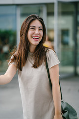 A young attractive Japanese tourist poses in a park during the day. She is pretty and smiling happily for her photograph.