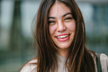 A close up photo of a young and attractive Japanese Asian woman. She has long black hair and is smiling widely as she looks into the camera. 